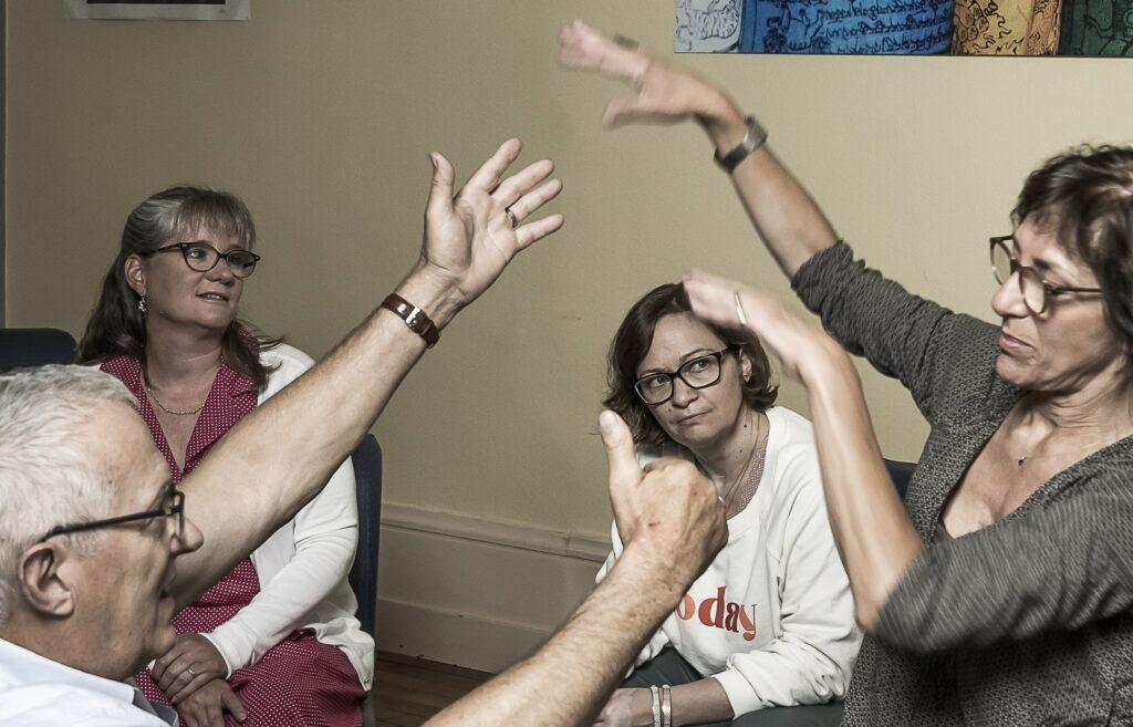 personnes dans un groupe de formation de gestalt-therapeute faisant des gestes vers le haut avec leurs bras ILFG
